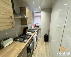 a small kitchen with a stove and a sink at 2 Bedroom Apartment by Central Serviced Apartments - Ground Floor - Monthly & Weekly Bookings Welcome - FREE Street Parking - Close to Centre - 2 Double Beds - WiFi - Smart TV - Fully Equipped - Heating 24-7 in Dundee