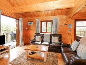 a living room with a leather couch and a table at Woodpecker Lodge in Langham