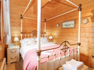 een slaapkamer met een hemelbed in een blokhut bij Woodpecker Lodge 