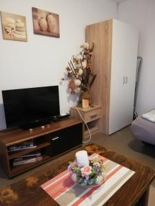 ein Wohnzimmer mit einem TV und einem Couchtisch in der Unterkunft Apartman "Vuković" in Bizovac