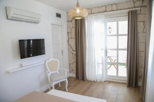 Habitación con TV, silla y ventana. en Alacati Balbadem Hotel, en Alacati