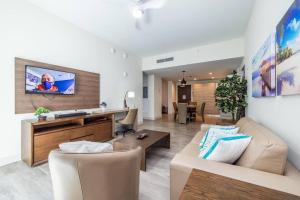 a living room with a couch and a tv at Luxury Beachfront Condo with Rooftop Pool in Hollywood