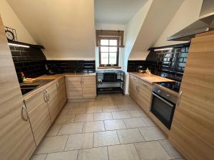uma grande cozinha com armários de madeira e piso em azulejo em Au Coeur des Collines, Noisette em Ellezelles