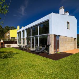 une maison avec de grandes fenêtres et une pelouse dans l'établissement Outeiro Villas Resort, à Barcelos