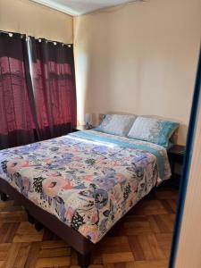 um quarto com uma cama com um edredão colorido em hostal NAUU em Concepción
