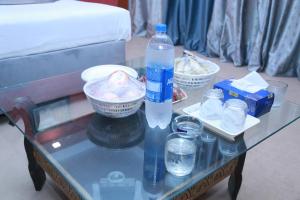 una mesa de cristal con una botella de agua y vasos. en Hotel palm east lahore en Lahore
