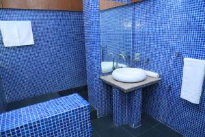 a blue tiled bathroom with a sink and a shower at Hotel palm east lahore in Lahore