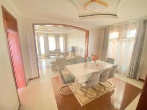een eetkamer met een witte tafel en stoelen bij Luxurious very spacious 6 bedrooms villa with pool located in Gacuriro,close to simba center and a 12mins drive to downtown kigali in Kigali