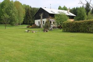 une maison noire et blanche dans une cour herbeuse dans l'établissement Chalupa bez hranic, à Krompach