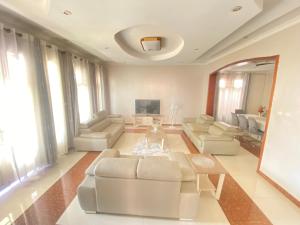 uma sala de estar com mobiliário branco e uma televisão em Luxurious very spacious 6 bedrooms villa with pool located in Gacuriro,close to simba center and a 12mins drive to downtown kigali em Kigali