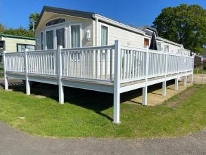 a mobile home with a white railing on the grass at Red Squirrel Lodge in Sandown