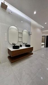 een badkamer met twee spiegels aan een muur bij منتجعات رغيد الفندقية in Hail