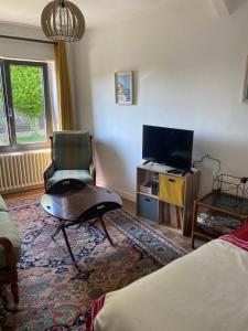 a living room with a chair and a flat screen tv at Charmante maison bretonne en pierre in Langourla