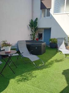 a lawn with chairs and a table and a hot tub at Petite maison indépendante in Le Havre