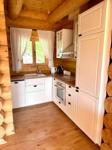 a kitchen with white cabinets in a log cabin at Sielska Chata Beskidy in Zawoja +18 photos