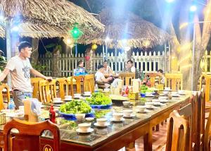 寧平的住宿－Ninh Binh Mountain View Homestay & Restaurant，站在长桌前吃着食物的人