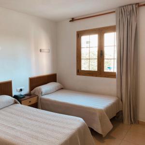 two beds in a room with a window at Pensión Torrecárdenas in Almería