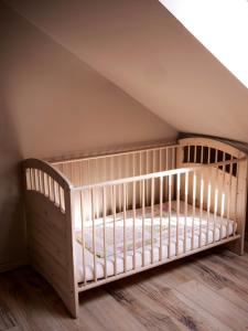 - un lit bébé dans une chambre mansardée avec un toit dans l'établissement Pipacs Apartman, à Tagyon