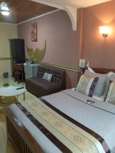 - une chambre avec un grand lit et un canapé dans l'établissement CONSTELLATION HOTEL, à Dschang