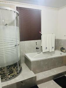uma casa de banho com um chuveiro e uma banheira em XG Guesthouse em Barkly East