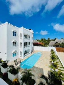 a large white building with a swimming pool in front of it at Ammerville Diani in Diani Beach