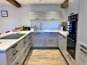 uma cozinha com electrodomésticos brancos e piso em madeira em Stunning 3-Bed Cottage in The Forest of Dean em Coleford