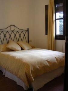 1 dormitorio con 1 cama grande con sábanas amarillas y ventana en Apartamento Rural Las Palmeras, en Almonaster la Real