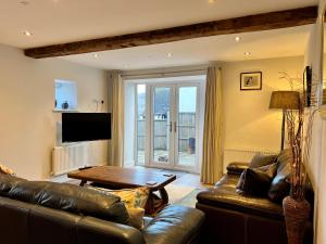 sala de estar con sofá de cuero y mesa en Stunning 3-Bed Cottage in The Forest of Dean en Coleford