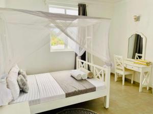 a bedroom with a white bed with a canopy at Ammerville Diani in Diani Beach