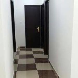 un pasillo con una puerta negra y un suelo a cuadros en GMR House, en Irbid