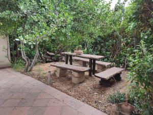 una mesa de picnic y dos bancos en un jardín en Villa Verde Guest House, en Tramatza