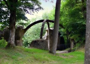 un arco in pietra in un parco con alberi e erba di chambres d'hôtes les frérots a Lurcy-le-Bourg