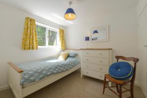 a bedroom with a bed and a dresser and a chair at April Cottage in Coverack