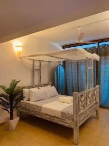 a bedroom with a canopy bed with a potted plant at Samara Studio Apartment - Diani Beachfront in Diani Beach