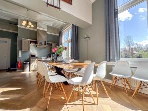 a dining room with a wooden table and white chairs at Weeshuis Groot in Enkhuizen