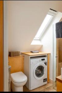 a bathroom with a toilet and a washing machine at Stans Place Self Catering Cottage in Malmesbury
