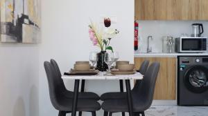 a table with chairs and a vase of flowers on it at Bright 2BR Retreat - Sleek Modern Living in Abu Dhabi