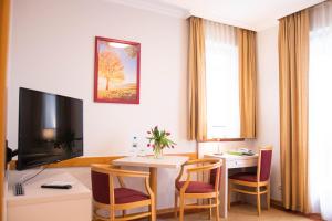 salon ze stołem i telewizorem w obiekcie Szalajka Liget Hotel és Apartmanházak w mieście Szilvásvárad