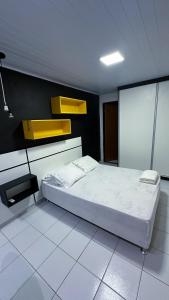 a bedroom with a white bed and yellow shelves at Sua Casa Francês in Marechal Deodoro +14 photos