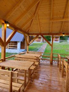 un gran pabellón de madera con mesas y bancos de madera en Wooden houses Bojovic en Gusinje