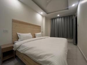 Tatsat Hostel في ريشيكيش: غرفة نوم بسرير ابيض كبير ونافذة