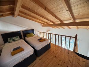 two beds in a room with wooden ceilings at Avra Benitses Beach Apartment in Benitses