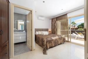 a bedroom with a bed and a bathroom with a balcony at Villa Hilary in Playa de Muro +42 photos