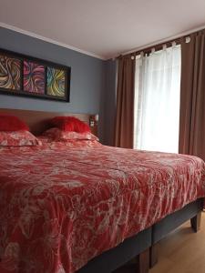 a bedroom with a bed with a red comforter and a window at Bellavista Dardignac 28 in Santiago