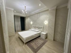 1 dormitorio con cama blanca y lámpara de araña en BAURUM Family Apartments, en Tashkent