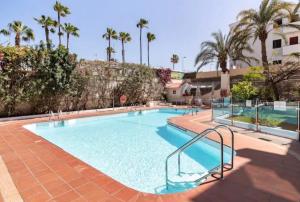a swimming pool with palm trees in a resort at Ocean blue 405 in San Bartolomé