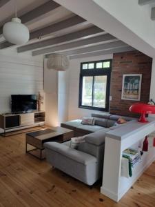 een woonkamer met een bank en een tv bij Maison Bel Air in Moliets-et-Maa