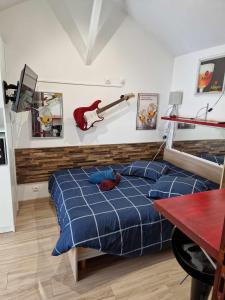 Razac-sur-lʼIsleにある07 - Joli studio avec vue sur jardin, parking privatif gratuit et accès gratuit au parc de la résidence ou des tables et fauteuils de jardins vous attendentのベッドルーム1室(ベッド1台付)、壁にギターが備わります。