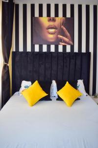 uma cama com almofadas amarelas e um cartaz na parede em Kahawa sukari luxury home em Nairobi