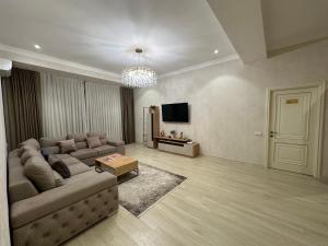 sala de estar con sofá y TV en BAURUM Family Apartments, en Tashkent